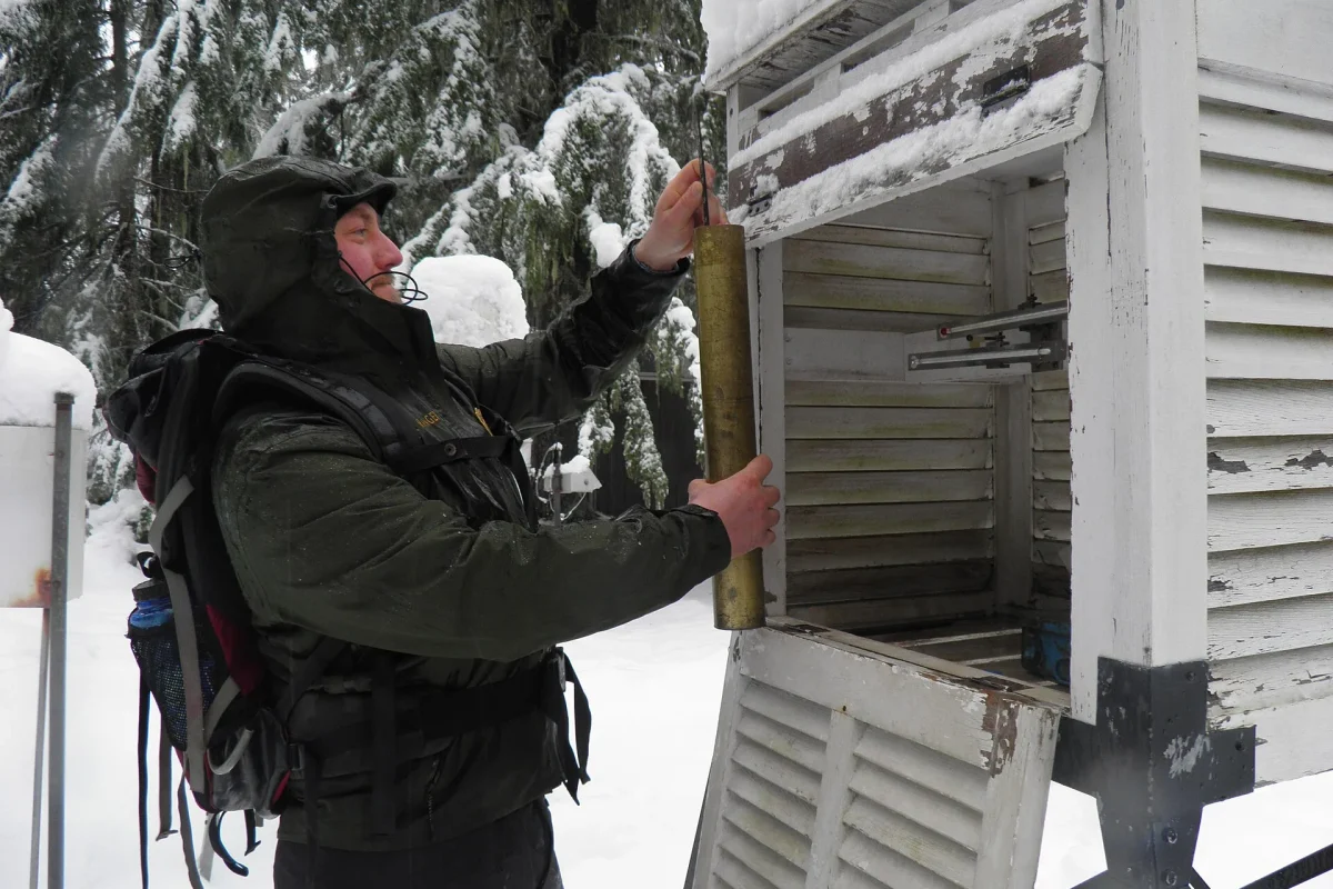Karlı arazide meteoroloji ölçüm kabinini kontrol eden görevli