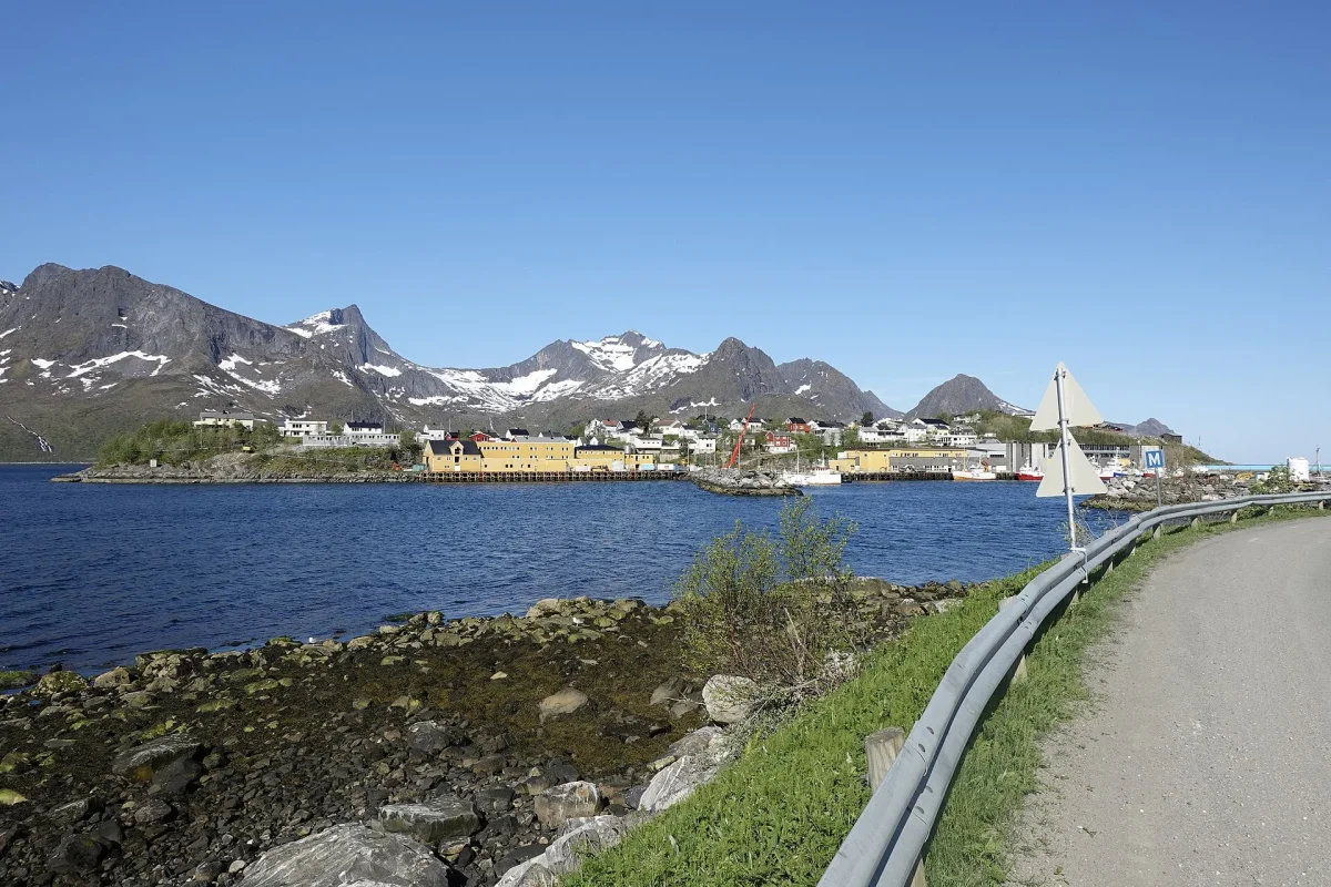 Norveç’te bir fiyortun kıyısındaki balıkçı köyü ve karlı dağlar