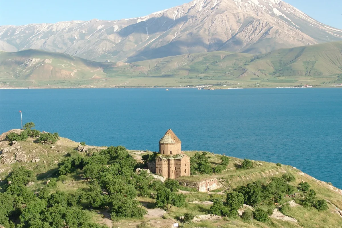 Van Gölü’nün turkuaz suyu, adadaki kilise ve arkadaki karlı dağ